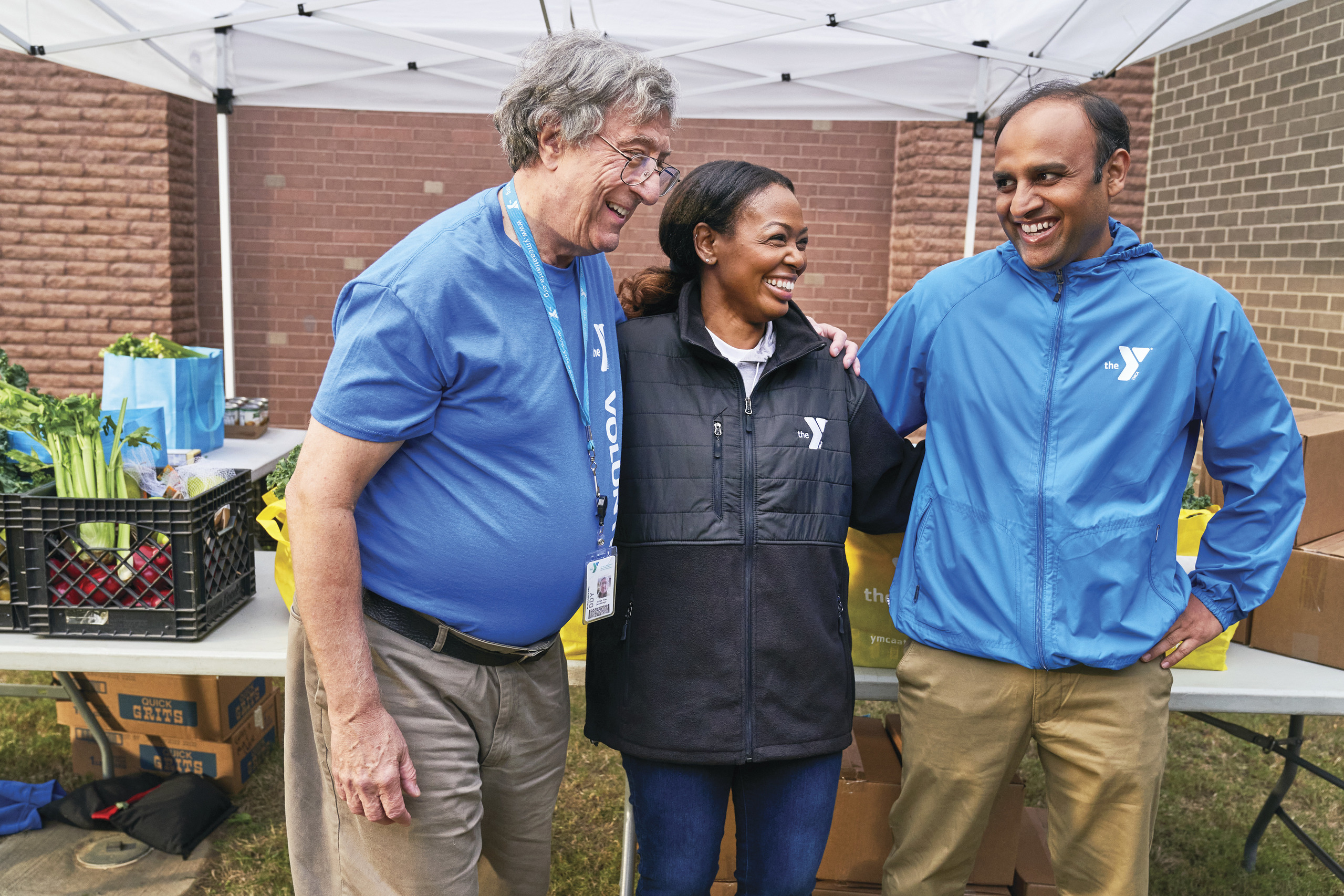 A group of friends smile while having fun at a ymca healthy food distribution event