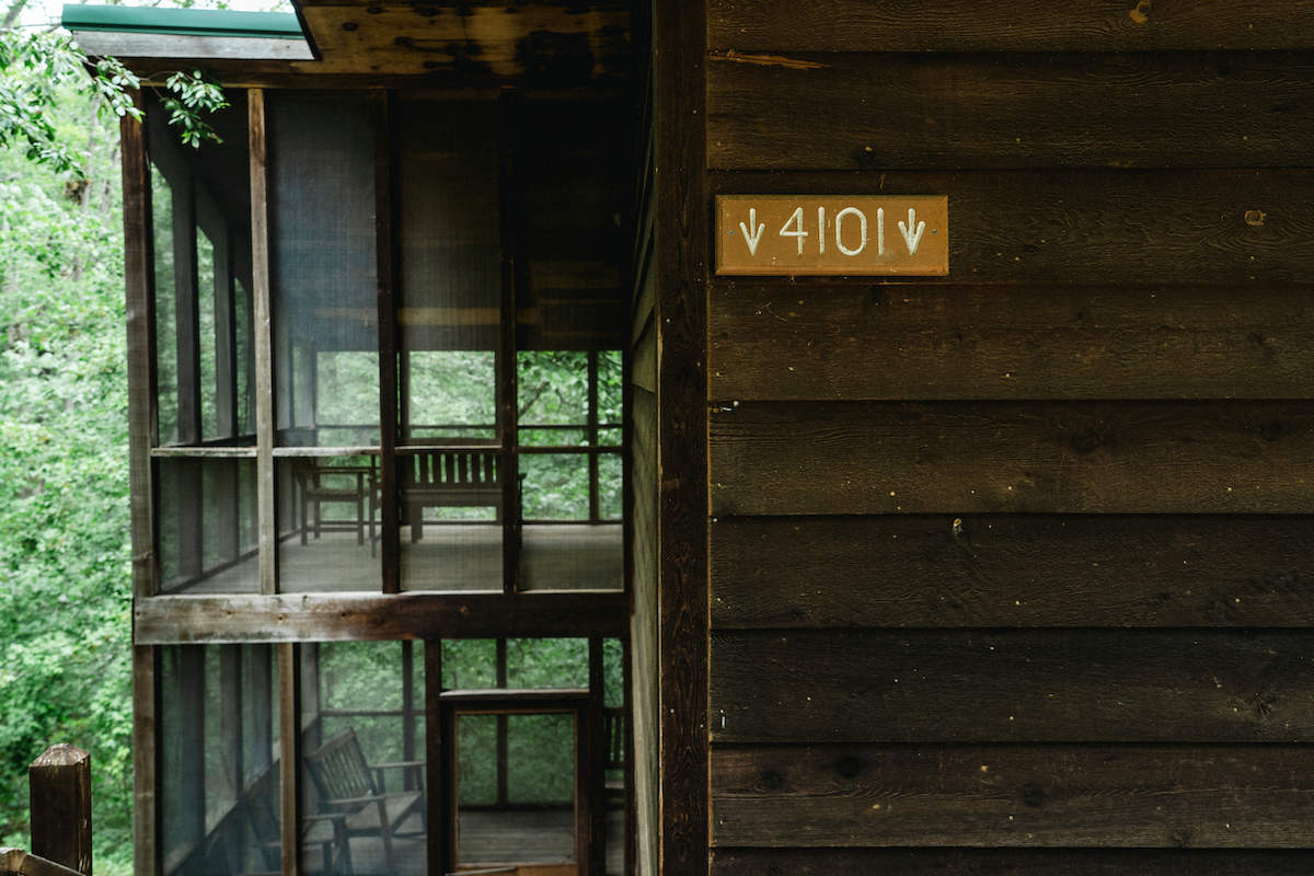Rustic wooden sign displaying the cabin number on the exterior of a Forest View Cabin at YMCA Trout Lodge.