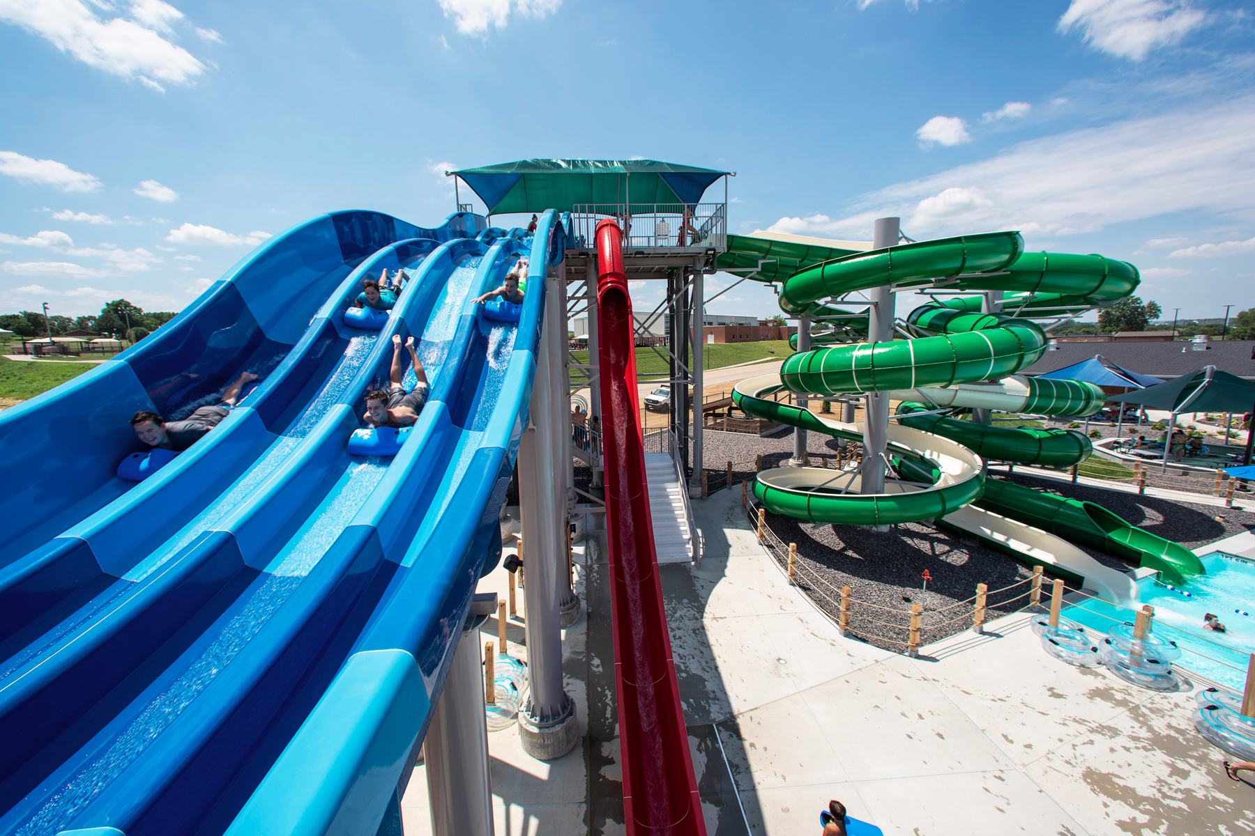 A thrill-seeker speeding down one lane of the multi-lane blue racer water slide, kicking up spray at the River Rapids Waterpark.