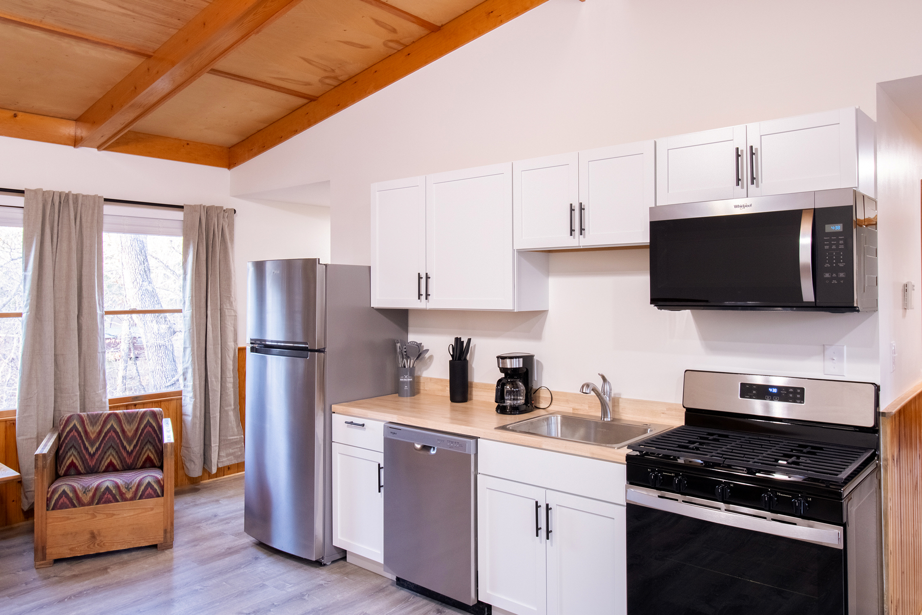 Deluxe Forest View Cabin Renovated Full Kitchenette featuring stainless steel appliances including a full fridge, dish washer, stove, and microwave.