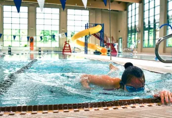 A woman swims laps in a ymca indoor swimming pool