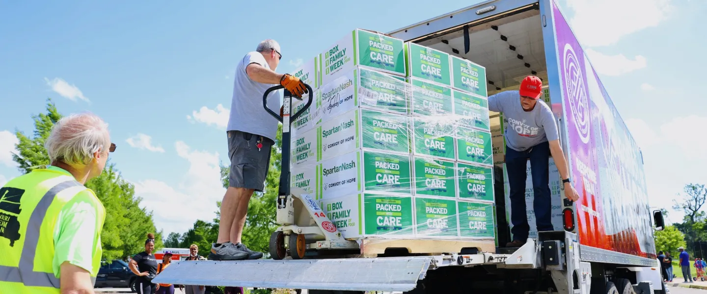 Volunteer unloading Convoy of Hope truck filled with boxed family meals for tornado relief distribution at the YMCA