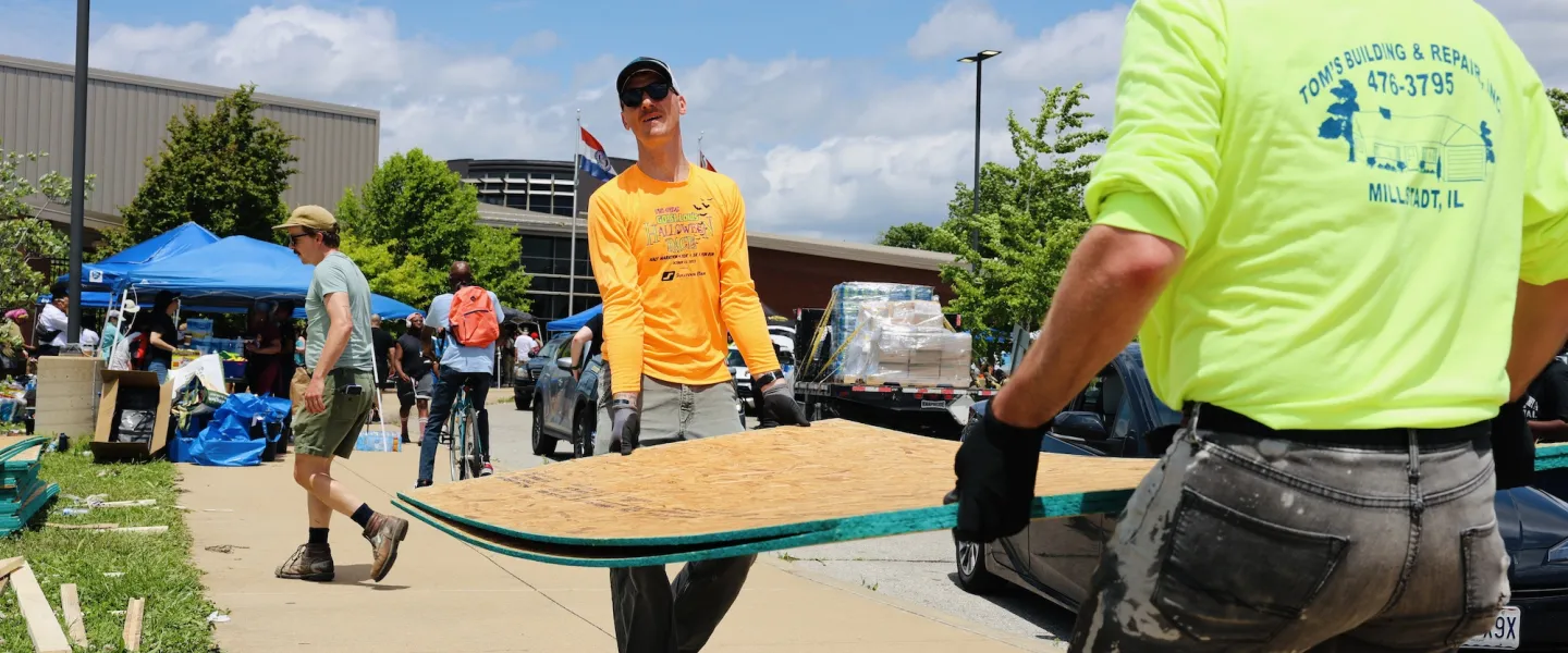 Group of YMCA volunteers carrying donated plywood sheets for tornado recovery efforts in St. Louis