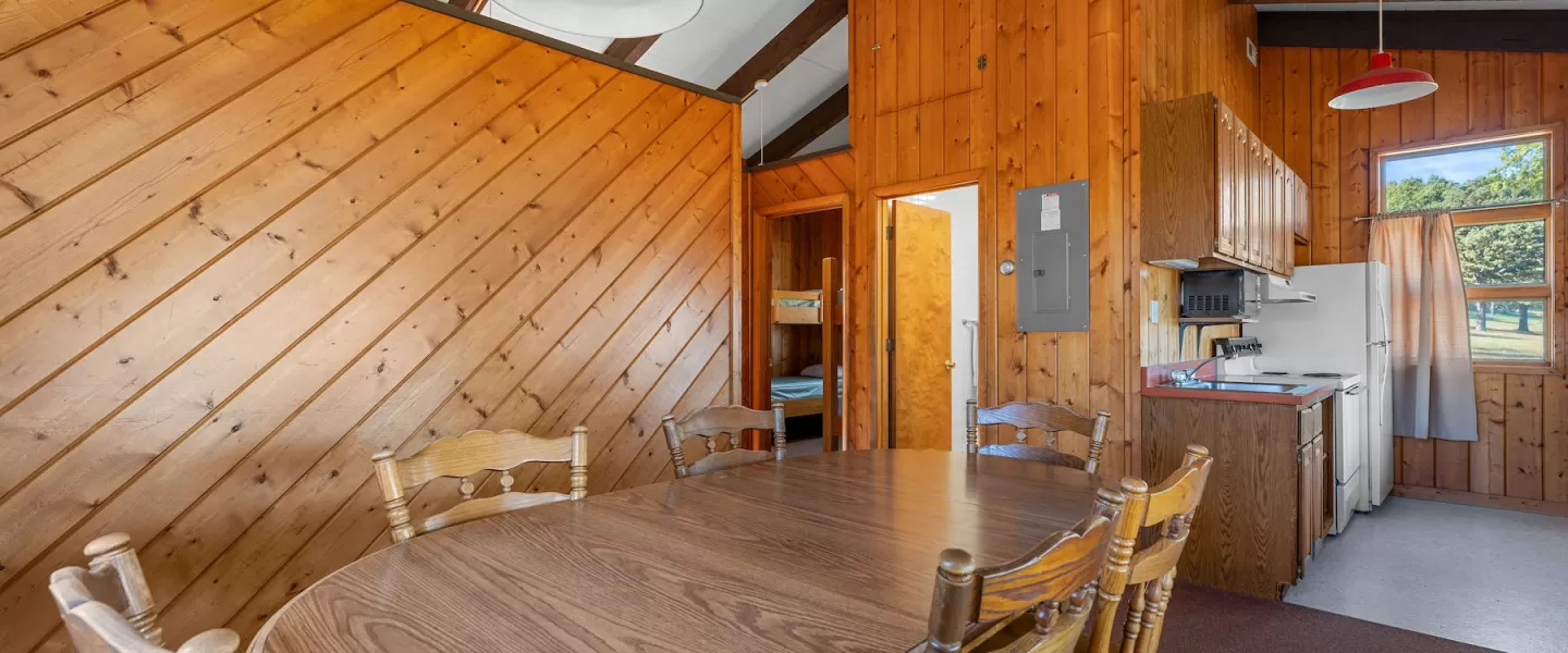Bluff View Cabin dining area with table and chairs leading into kitchenette area and bedrooms