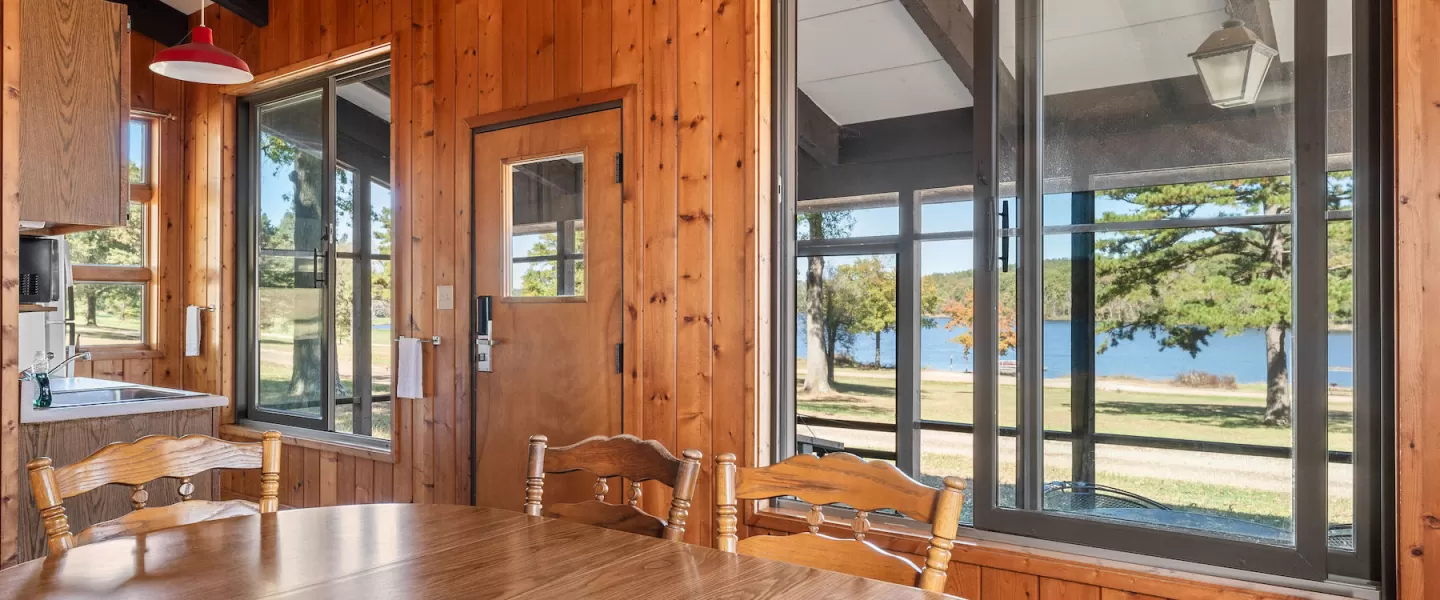 Bluff View Cabin dining area with table and chairs in front of lake-facing windows with views of Sunnen Lake