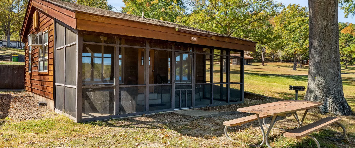 Exterior of Bluff View Cabin with screened-in porch, picnic table, and charcoal grill near Sunnen Lake
