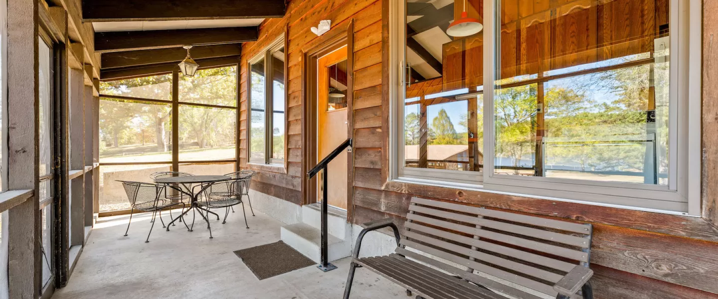 Screened-in porch at Bluff View Cabin with patio furniture and wooden bench seating overlooking wooded surroundings