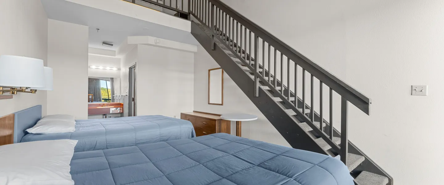 Wide view of Trout Lodge Loft Room with two queen beds, large windows, and warm wood accents