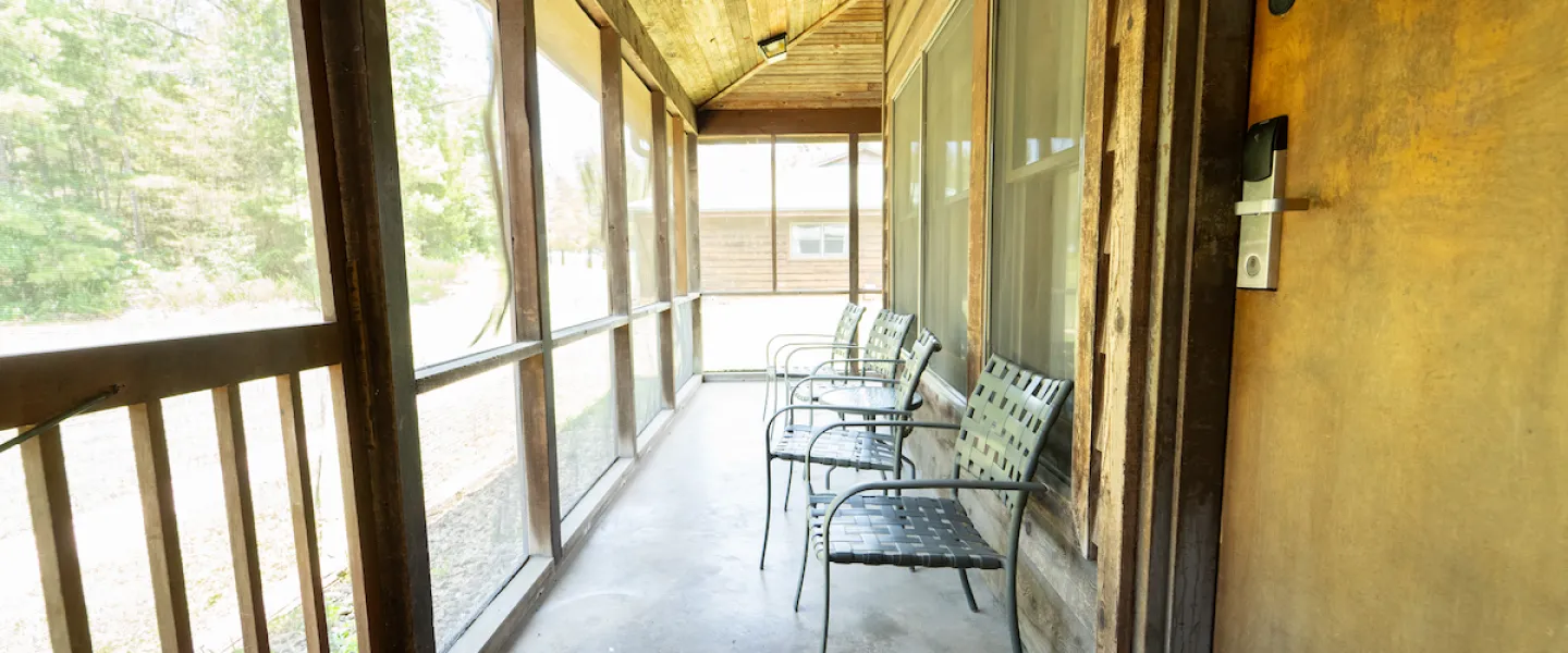 Screened porch with patio chairs attached to a Lake View Cabin at YMCA Trout Lodge in Potosi, Missouri