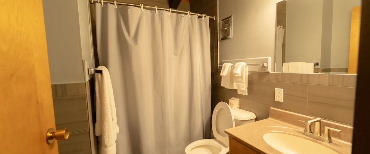 Bathroom in a Lake View Cabin at Trout Lodge featuring a shower and tub combo, vanity sink, and towels provided.