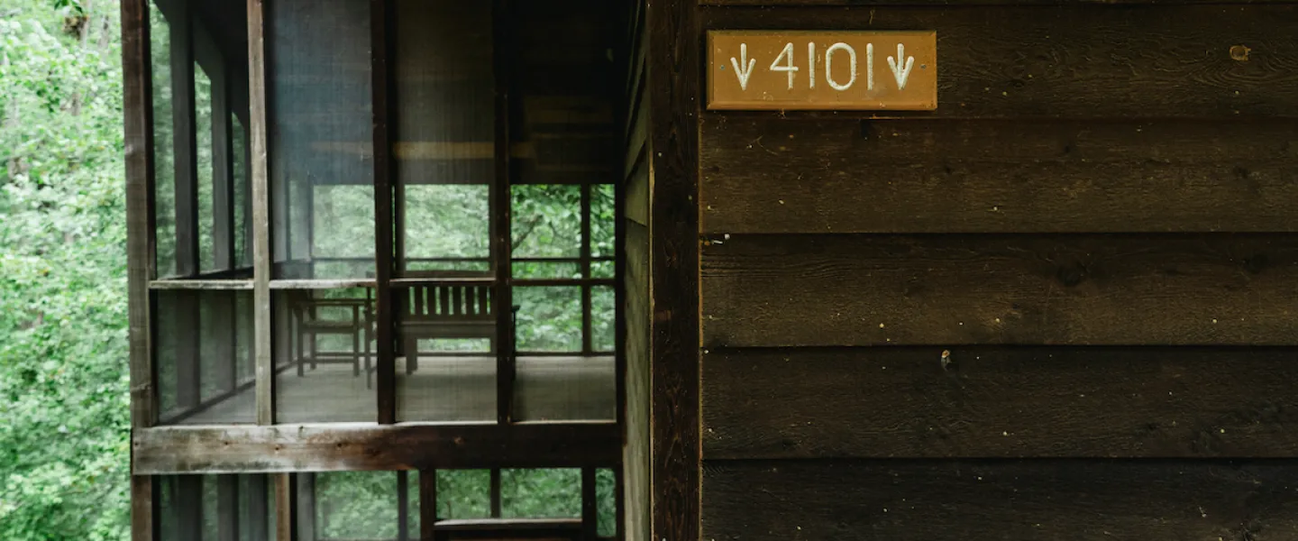 Rustic wooden sign displaying the cabin number on the exterior of a Forest View Cabin at YMCA Trout Lodge.