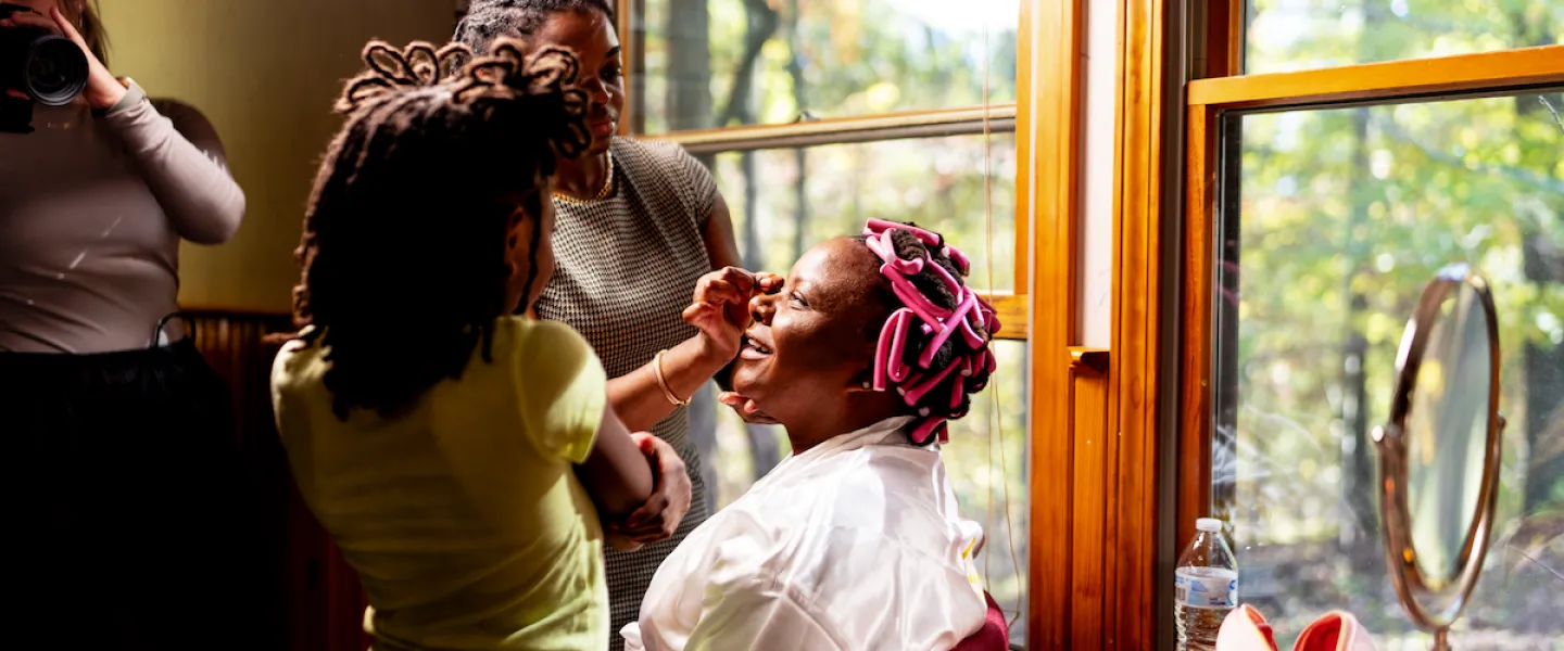 A bride gets her final makeup touches in a rustic cabin room before her Trout Lodge wedding ceremony.
