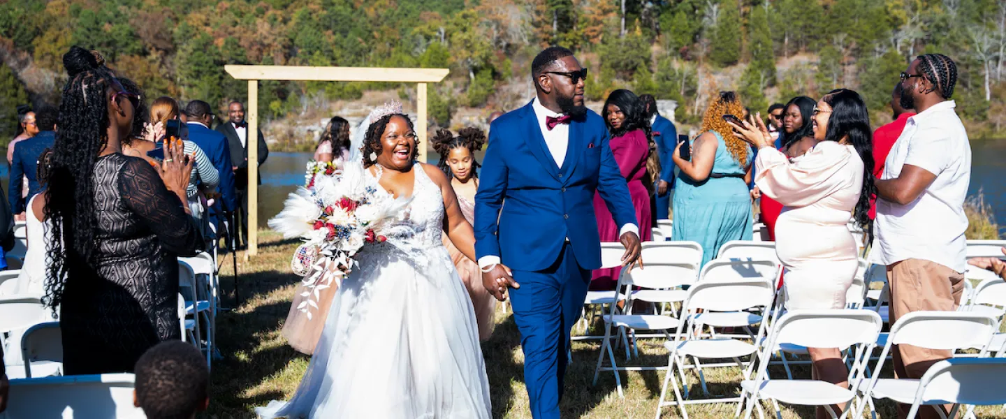 Newly married couple walking down the isle in their outdoor wedding venue next to the Sunnen Lake Bluffs at YMCA Trout Lodge.