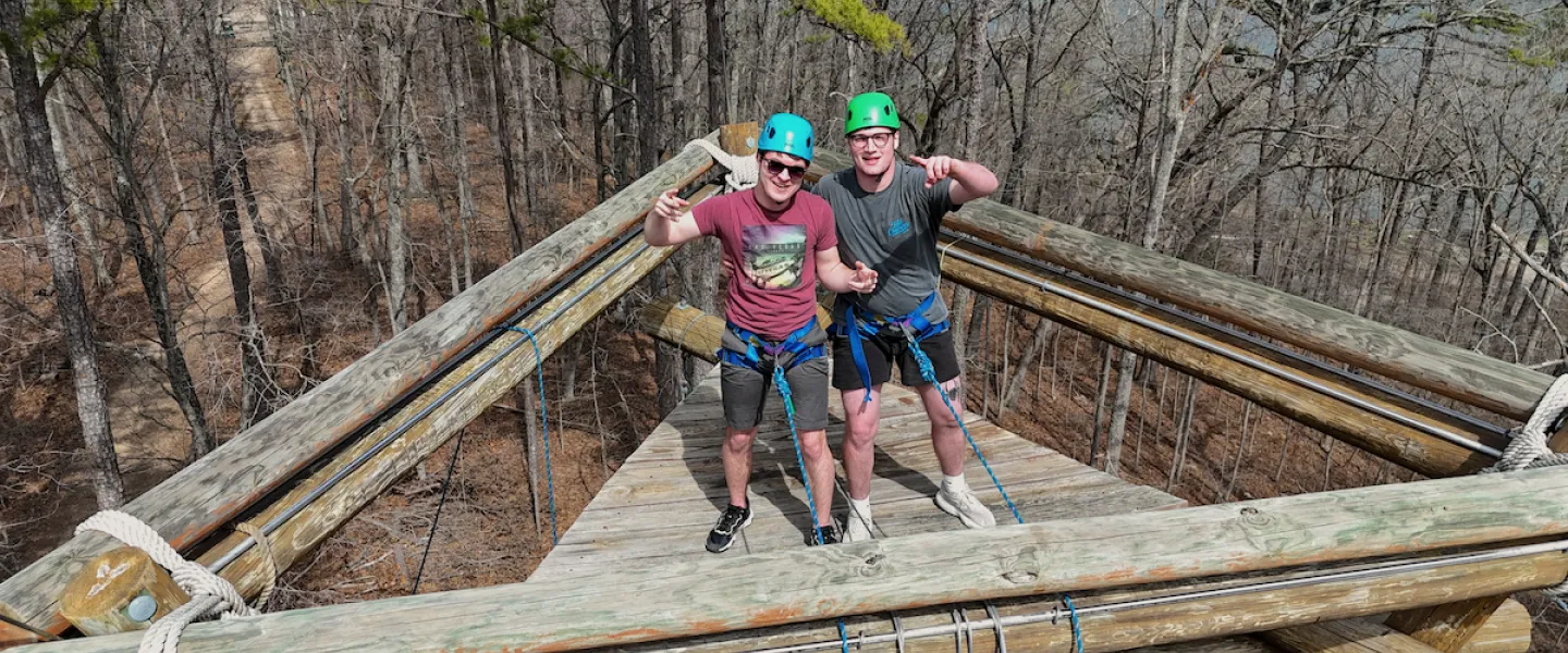 Two colleagues climbing to the top of the YMCA Trout Lodge Alpine Tower as part of an IMPACT Team-Building Program activity.