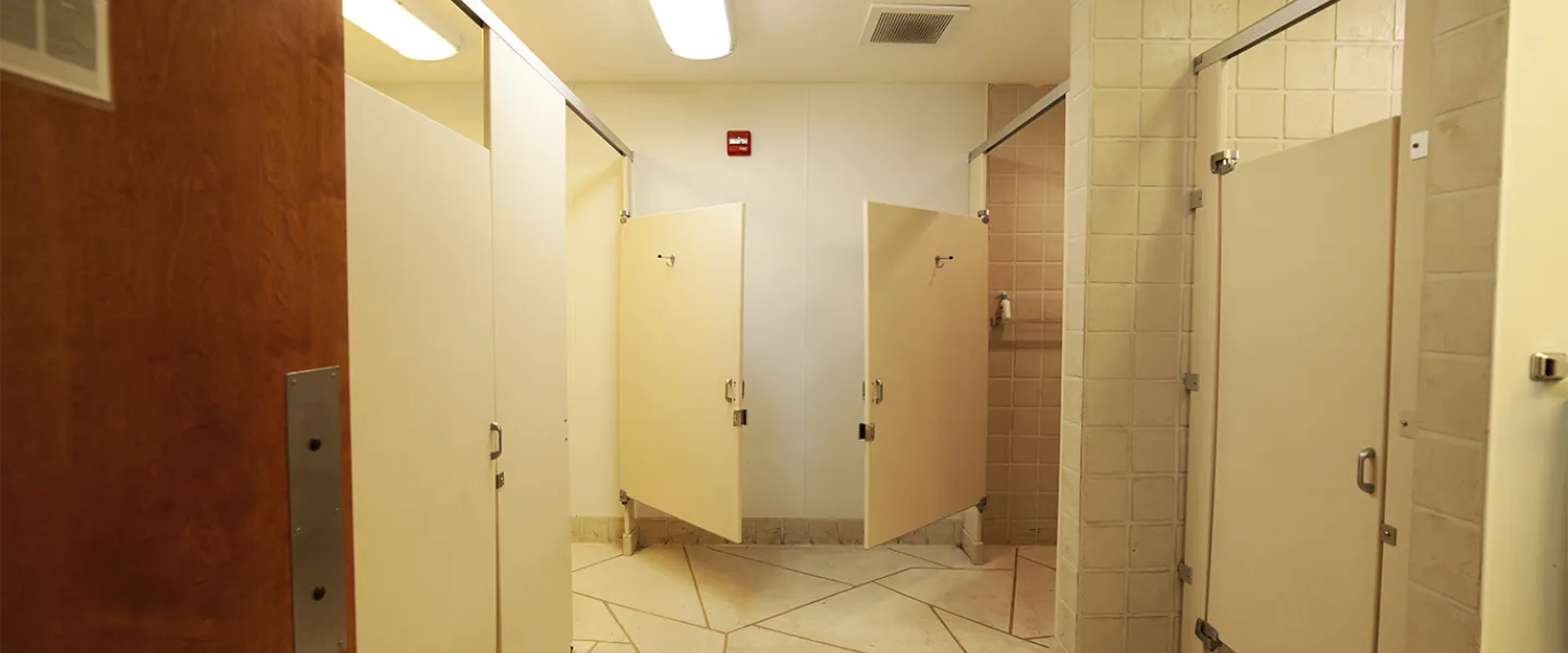 A clean, modern Main Camp bathroom, showing a row of private toilet stalls and sinks.