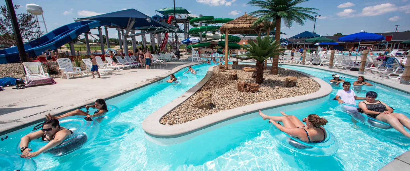 Guests relaxing in inner tubes while floating down the winding lazy river under a sunny sky at the Ste. Genevieve YMCA River Rapids Waterpark.