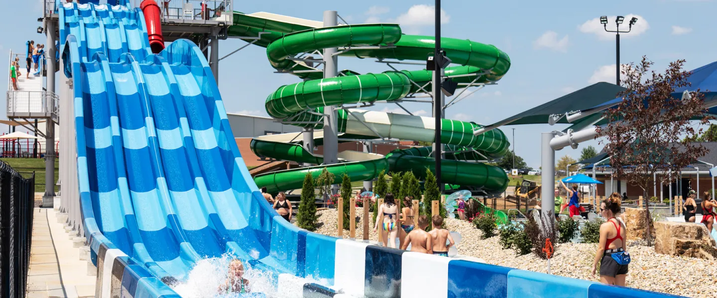 A thrill-seeker speeding down one lane of the multi-lane blue racer water slide, kicking up spray at the River Rapids Waterpark.