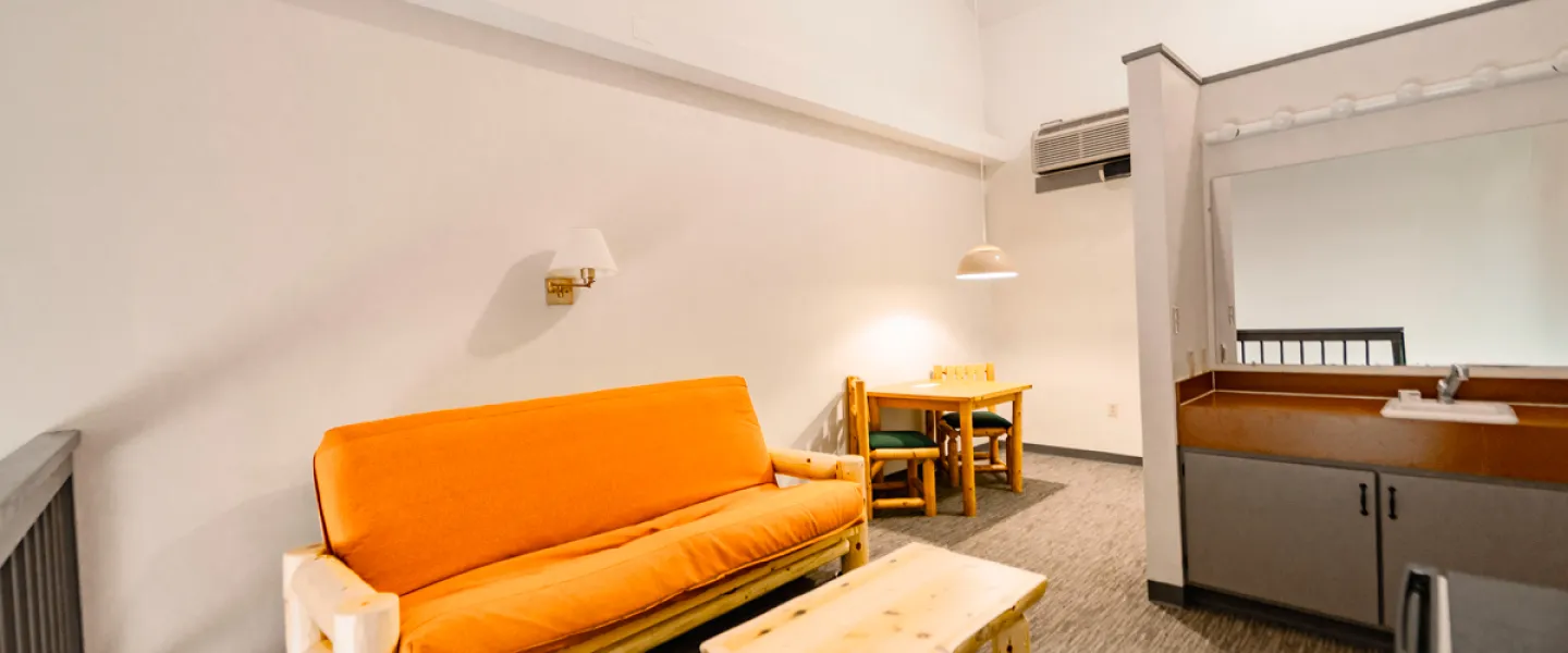An interior shot of the upper loft area of the Loft Guest Rooms showing the living space with mini fridge and sleeper sofa
