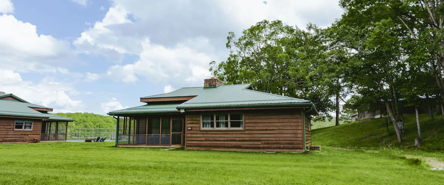 An exterior shot of a YMCA Trout Lodge Lake View Cabin featuring a screened in porch and view of Sunnen Lake shores.