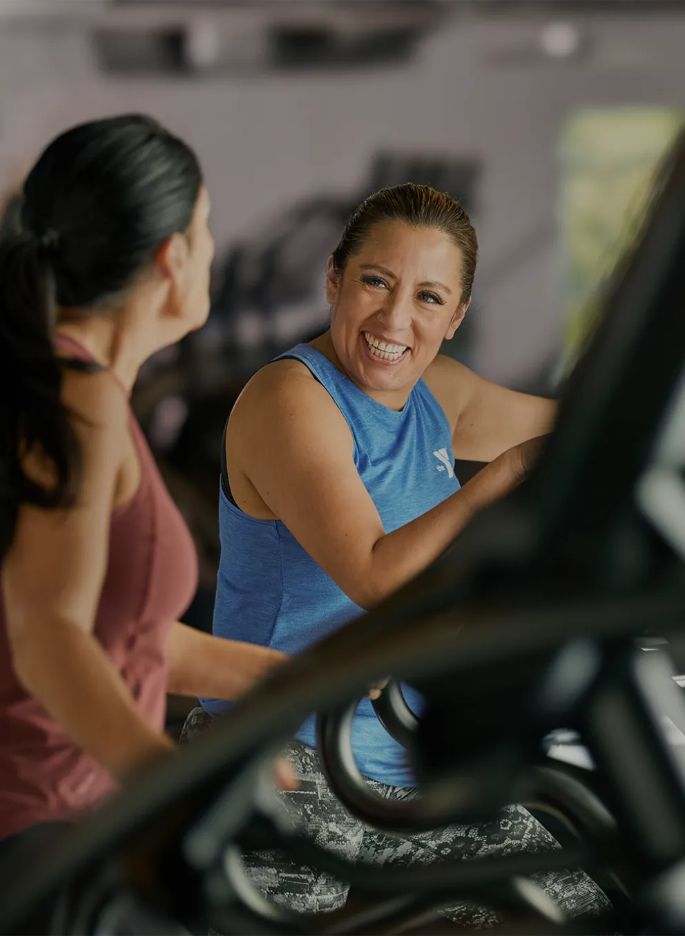 Two Women Laugh as they Workout in a YMCA Fitness Center