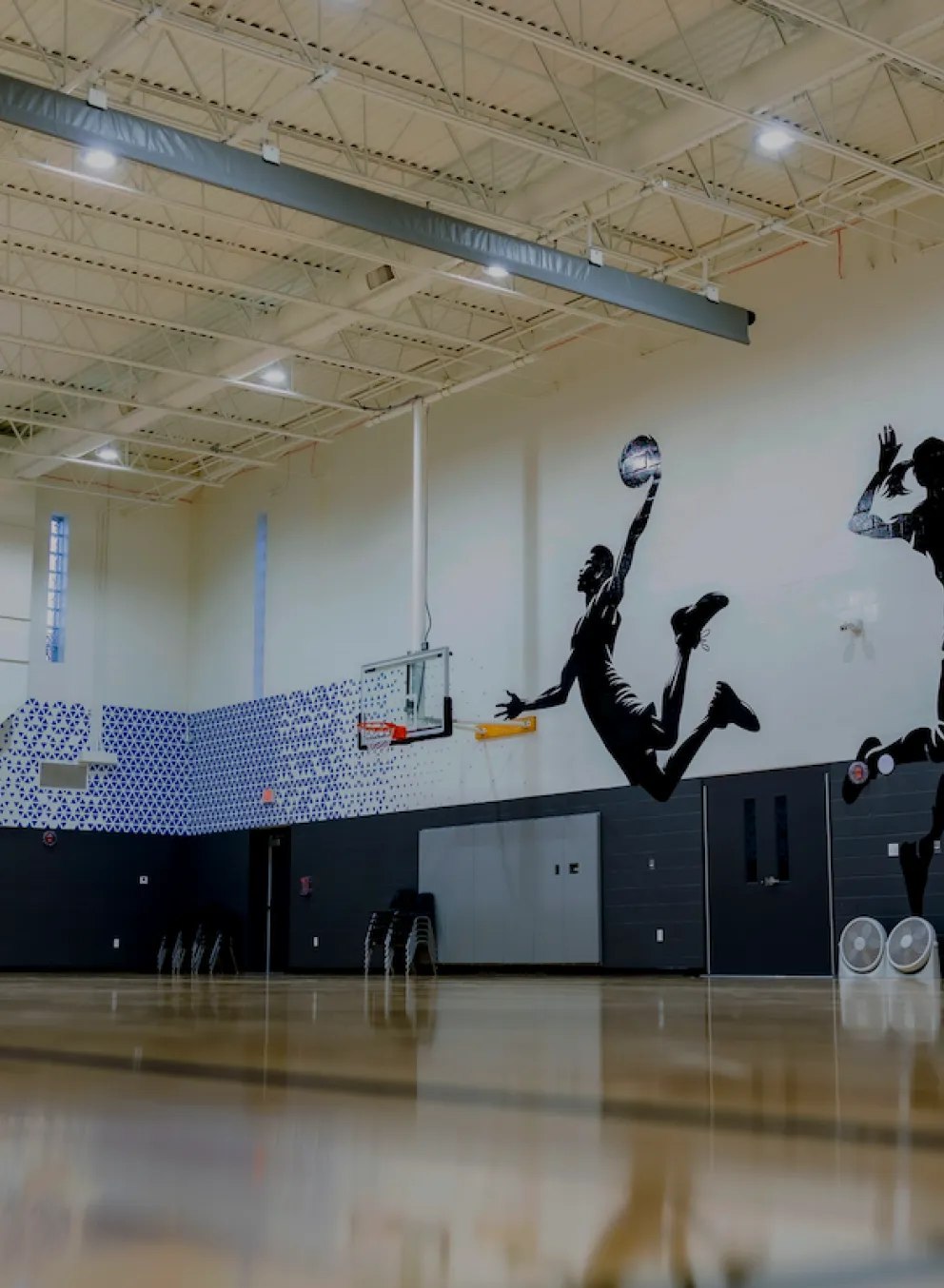 Newly renovated basketball and sports gymnasium at the O'Fallon Missouri YMCA featuring new flooring, pain, and decorative decals on the gym walls