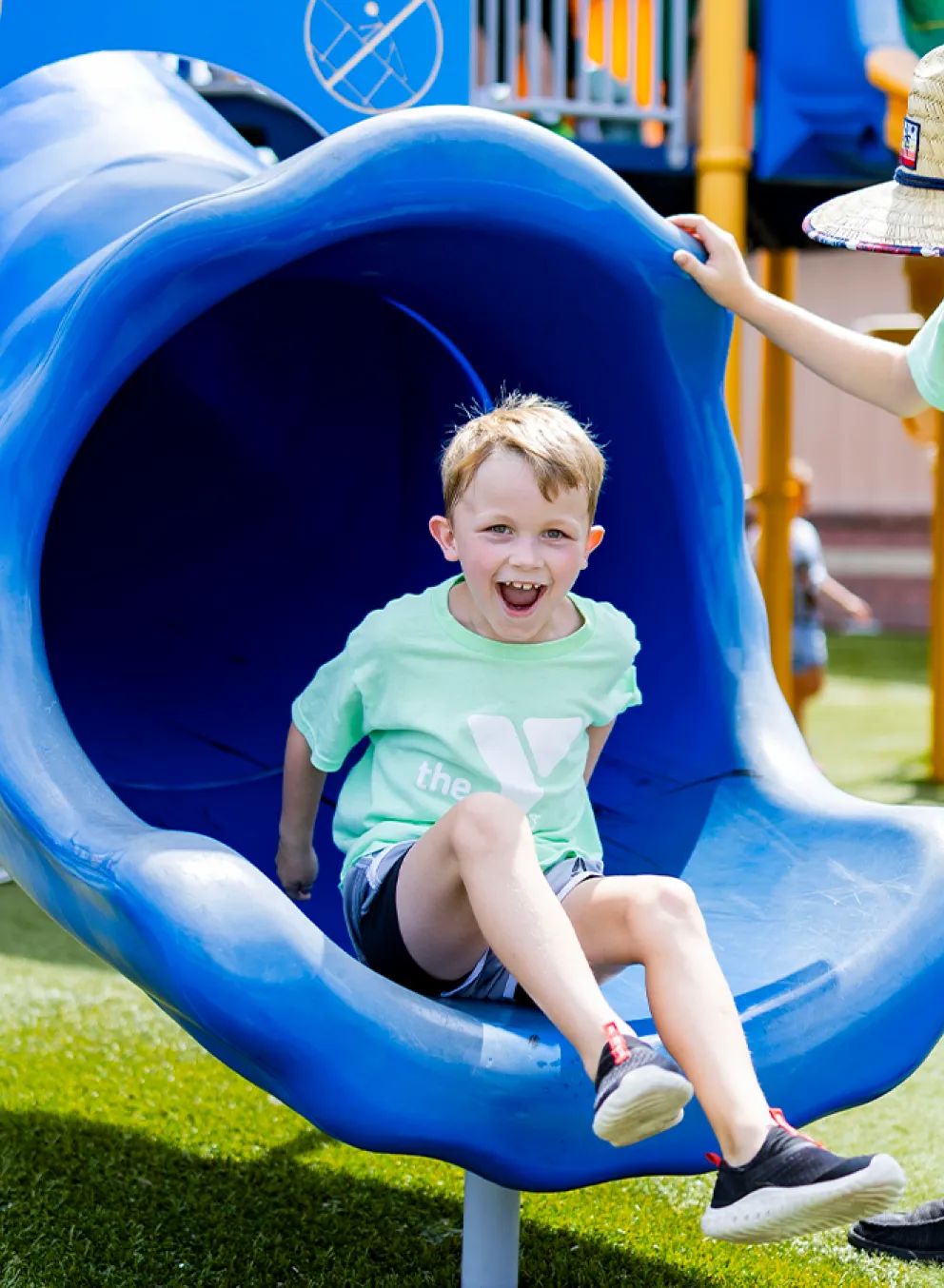 Two YMCA Summer Day Camp participants playing on a playground in matching YMCA field trip t-shirts.