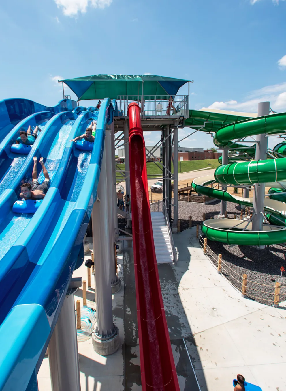 A thrill-seeker speeding down one lane of the multi-lane blue racer water slide, kicking up spray at the River Rapids Waterpark.