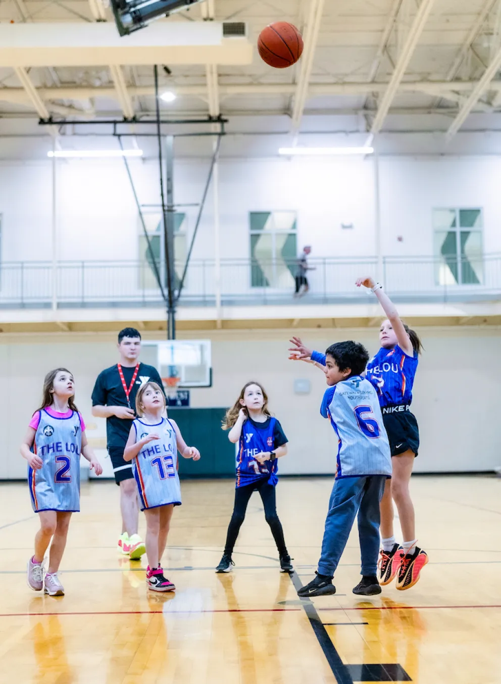 A young girl shoots a basketball attempting to score in a YMCA Youth Basketball game.