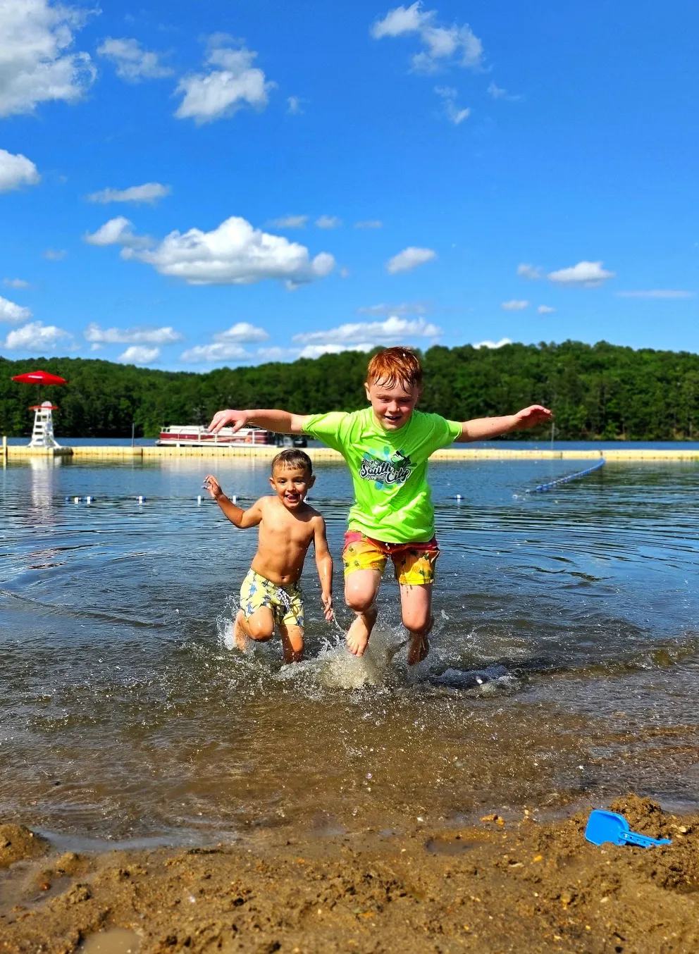 Two children splash in the water of Sunnen Lake's beachfront at YMCA Trout Lodge