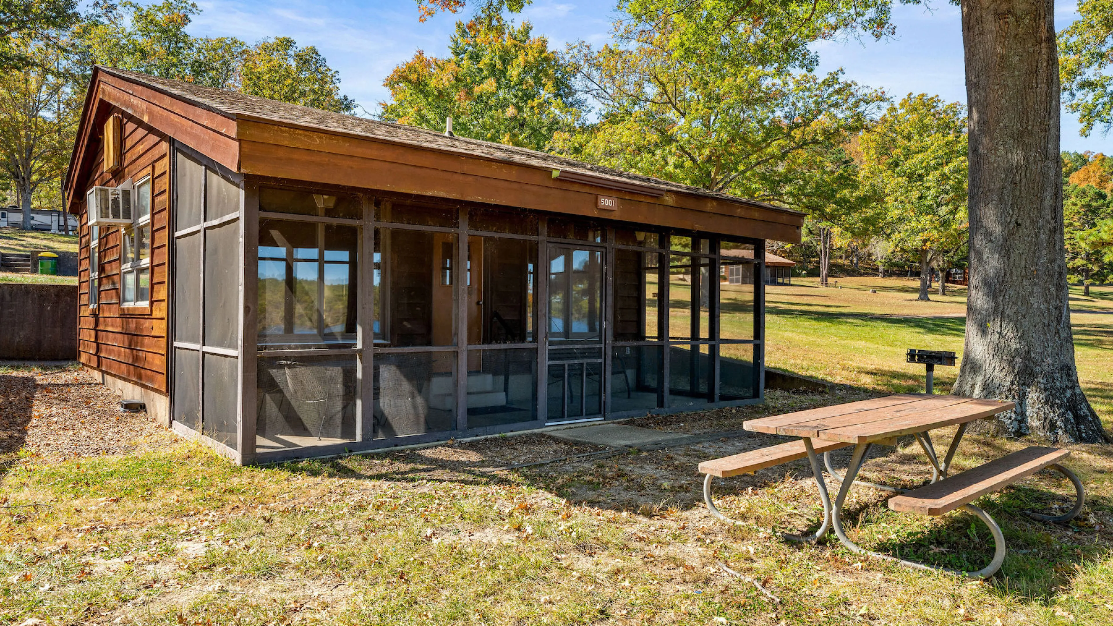 Exterior of Bluff View Cabin with screened-in porch, picnic table, and charcoal grill near Sunnen Lake