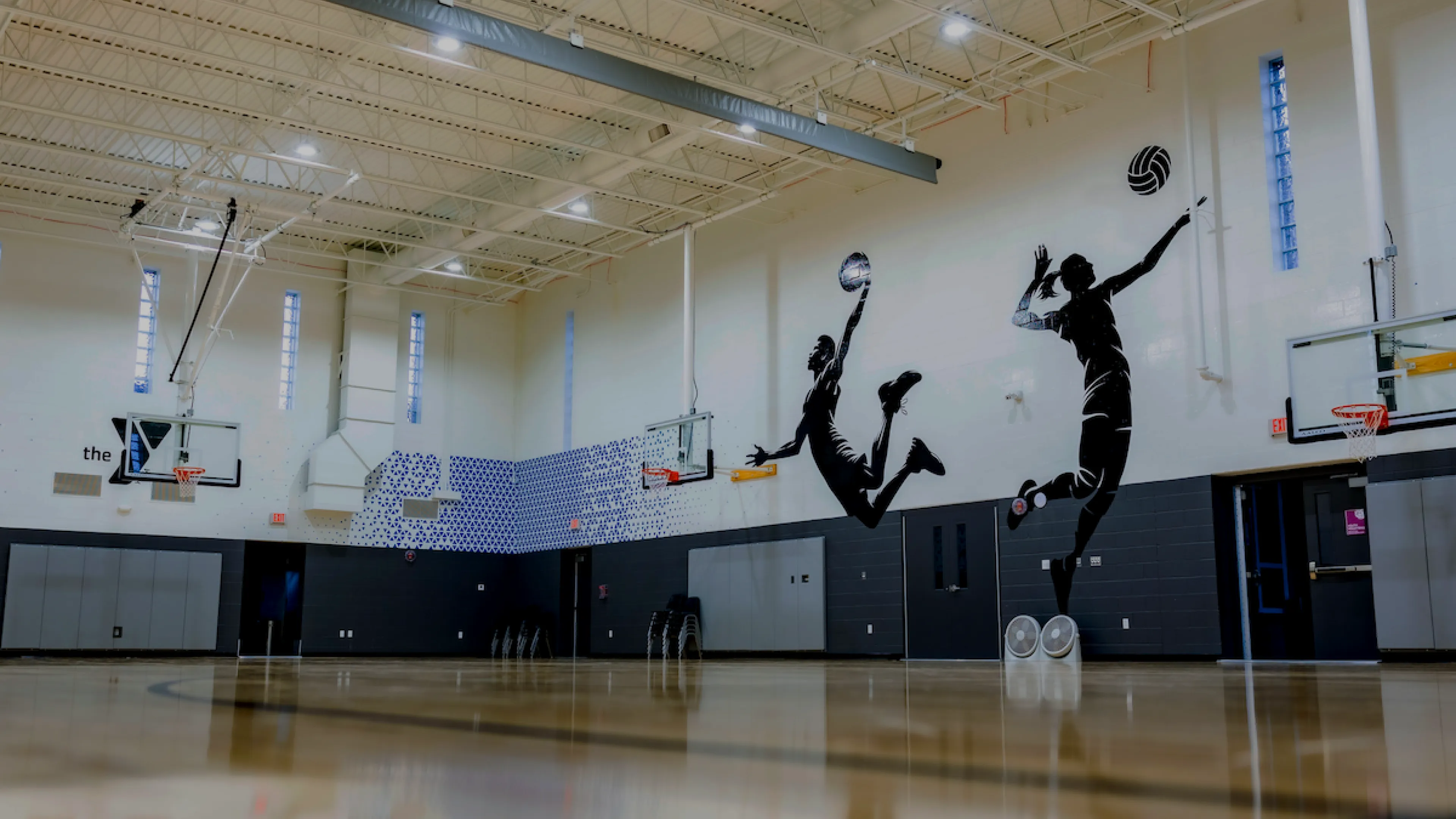 Newly renovated basketball and sports gymnasium at the O'Fallon Missouri YMCA featuring new flooring, pain, and decorative decals on the gym walls