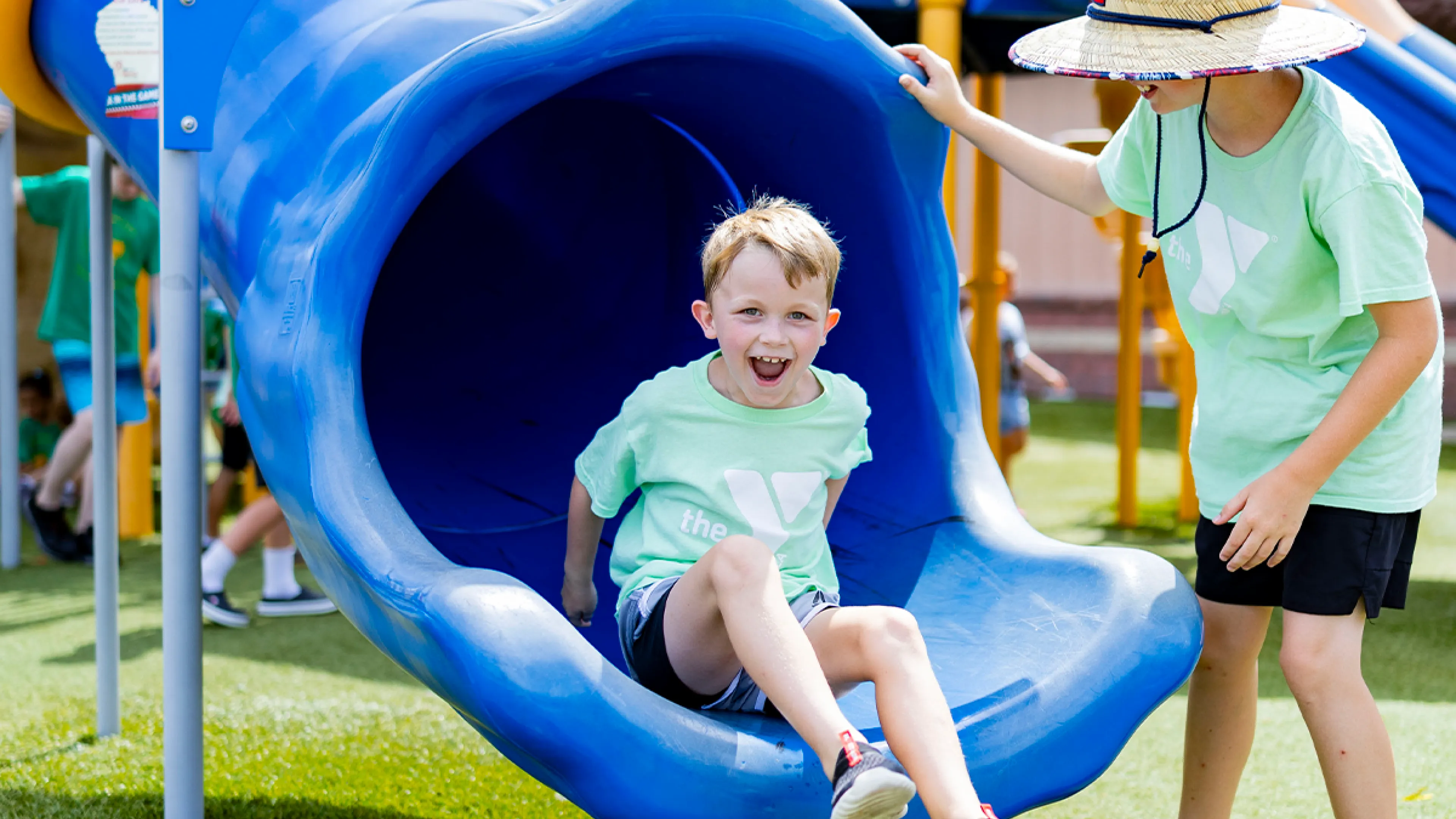 Two YMCA Summer Day Camp participants playing on a playground in matching YMCA field trip t-shirts.