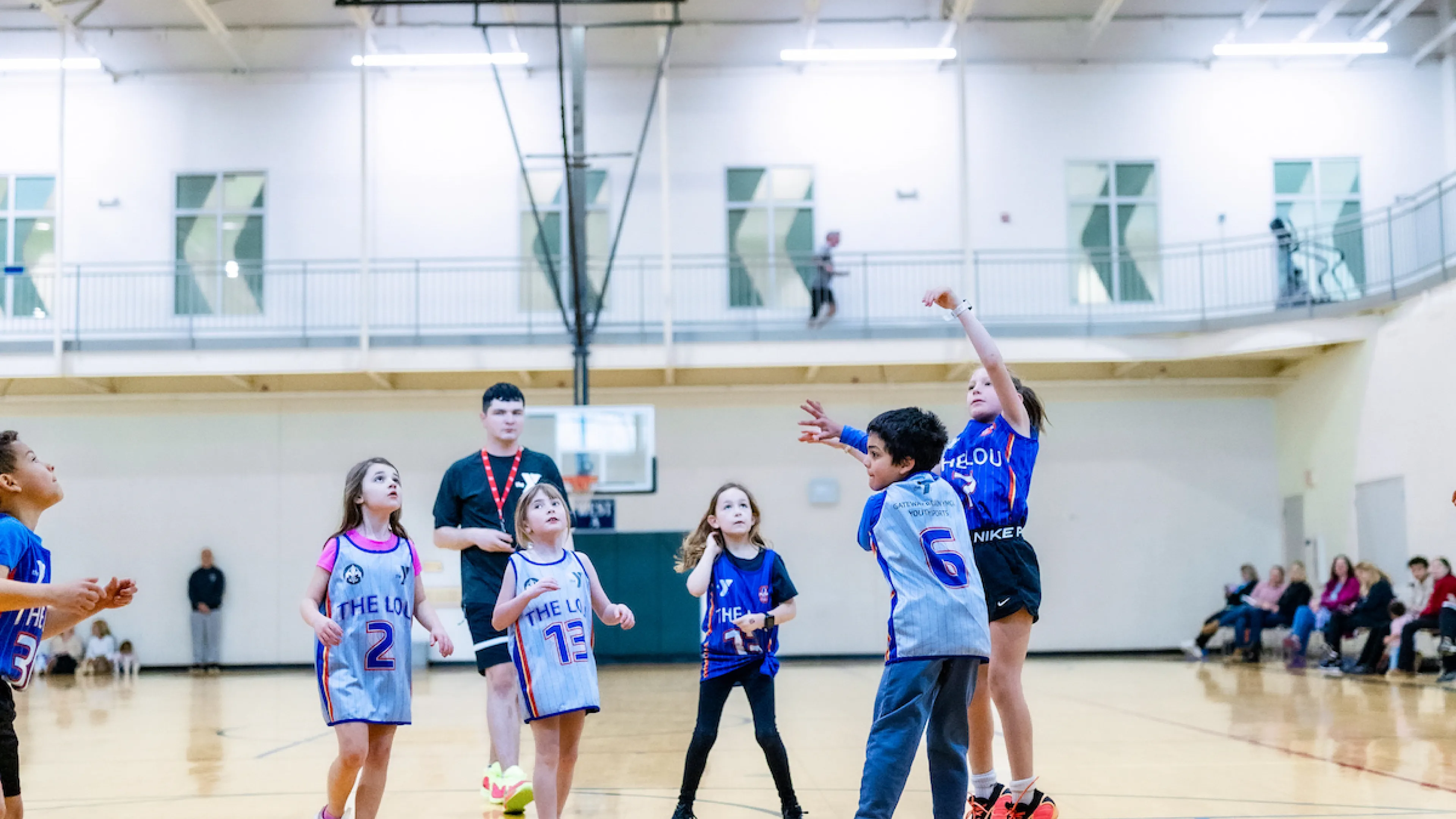 A young girl shoots a basketball attempting to score in a YMCA Youth Basketball game.