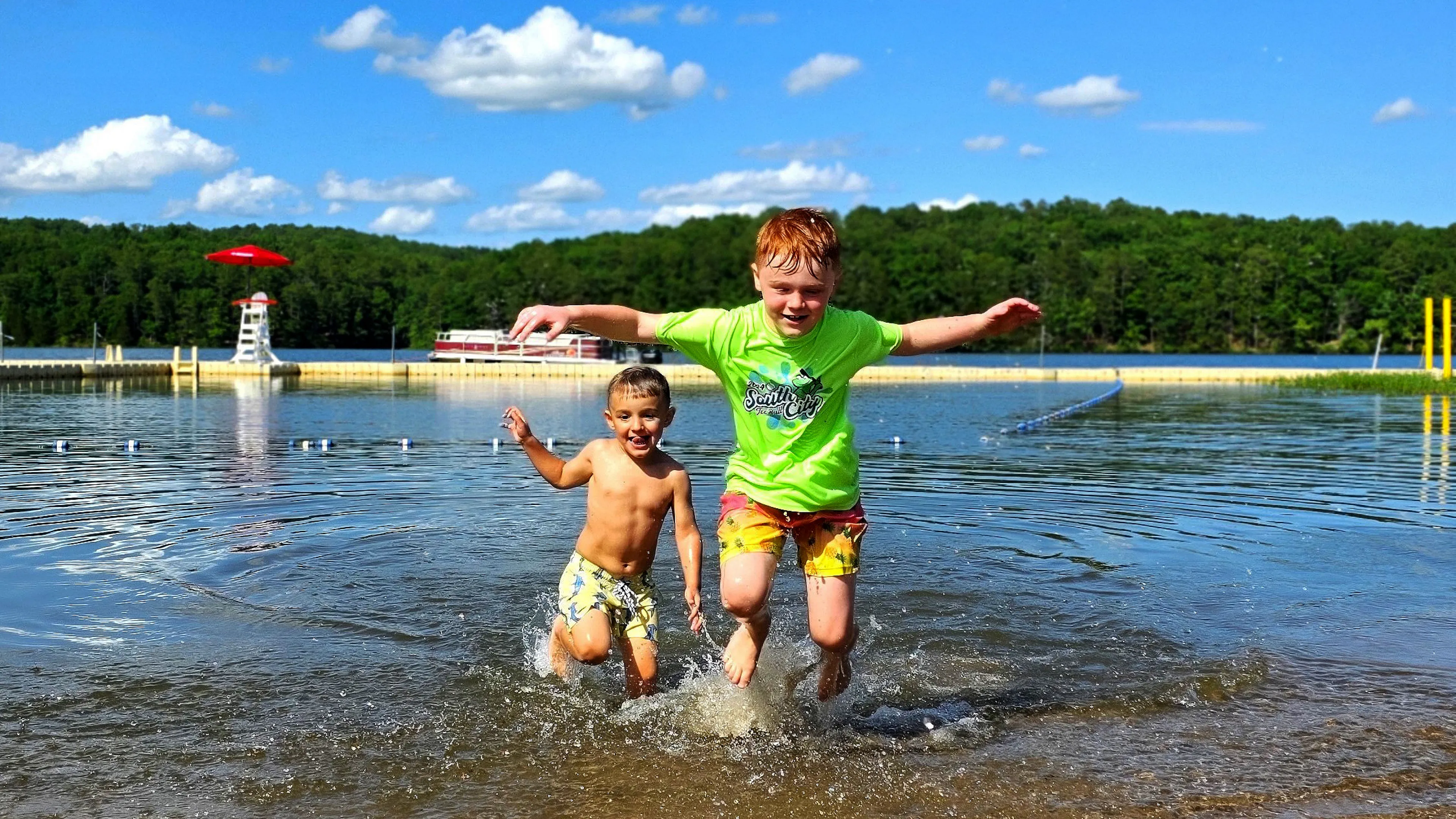 Two children splash in the water of Sunnen Lake's beachfront at YMCA Trout Lodge