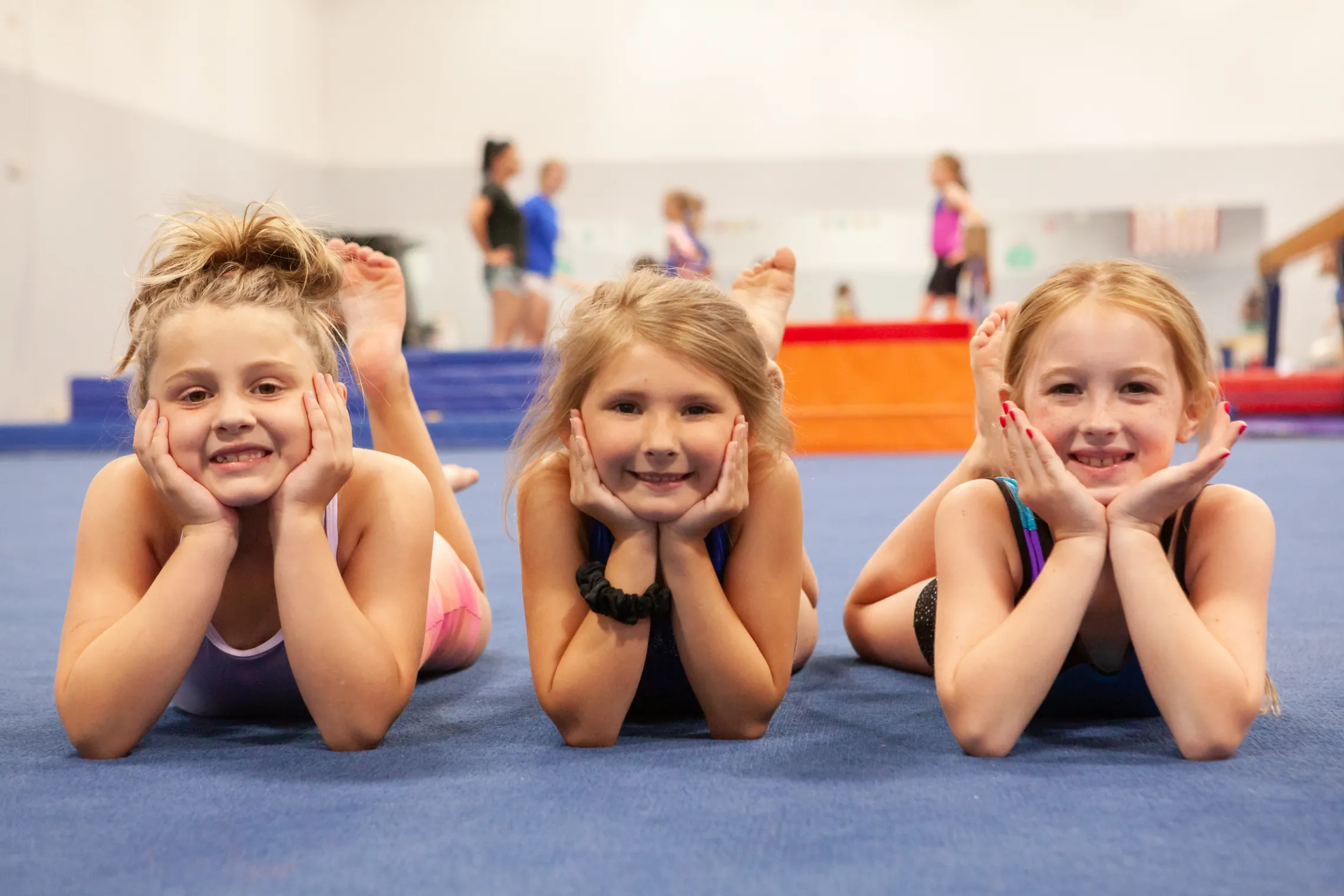 three girls pose and smile in a ymca gymnastics class