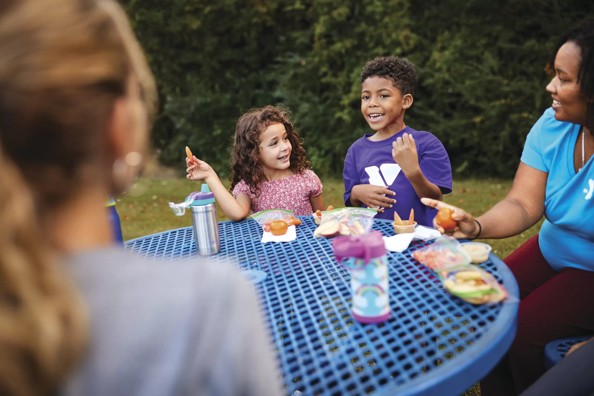 Children sit at a picnic table eating healthy foods that improve bone health
