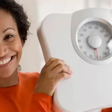 woman smiling holding a scale in her hands