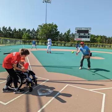 An adaptive sports participant and his buddy bat in an adaptive baseball game.