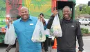 Thumbnail: An image of two African American men posing in front of the YMCA's Metro Market Bus. They are enthusiastically holding up bags of food in their hands.