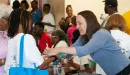 Thumbnail: An image of a Caucasian volunteer at the YMCA's backpack give-away assisting a young African American female and her grandmother. There is a group of middle-aged African American females and males also visible in the background.