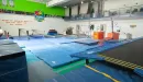 Thumbnail: Gymnastics room with balance beams, trampoline, parallel bars, and soft floors. Upstairs viewing area for parents.