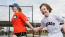 Thumbnail: Adaptive sports participant runs holding hands with sports buddy smiling