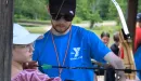 Thumbnail: Staff helping camper shoot bow and arrow