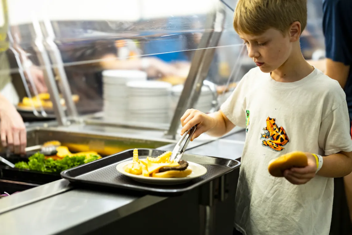 Burger bar station with grilled patties, buns, and customizable toppings