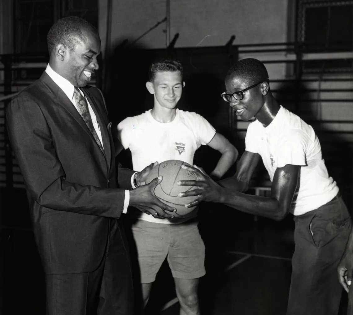 A historical photo of the Gateway Region YMCA association's Downtown St. Louis YMCA location with a coach and young basketball participant in the gymnasium.