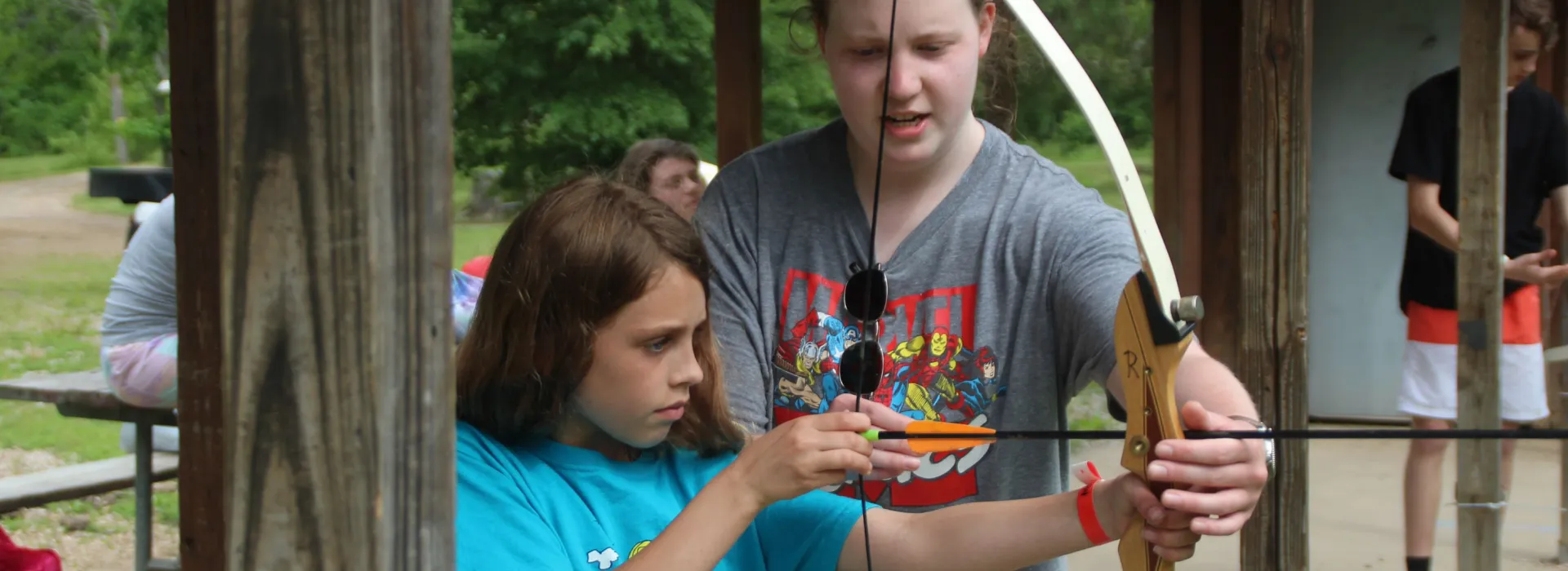 young woman helping a girl at the archery range
