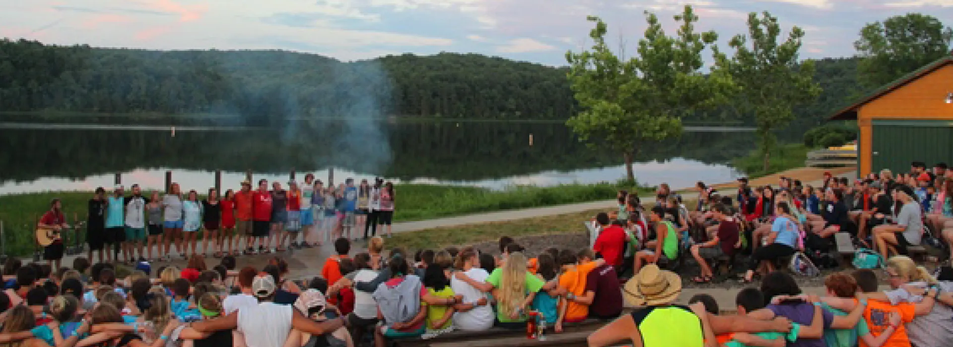 group seated at campfire overlooking the lake