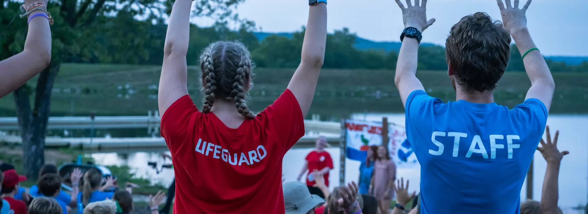 Staff raising arms at campfire