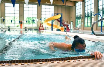 A woman swims laps in a ymca indoor swimming pool