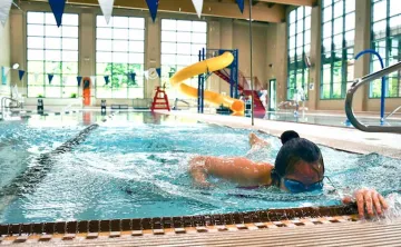 A woman swims laps in a ymca indoor swimming pool